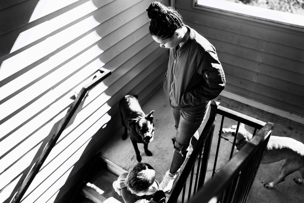 A woman walks down a stairwell with her three dogs 