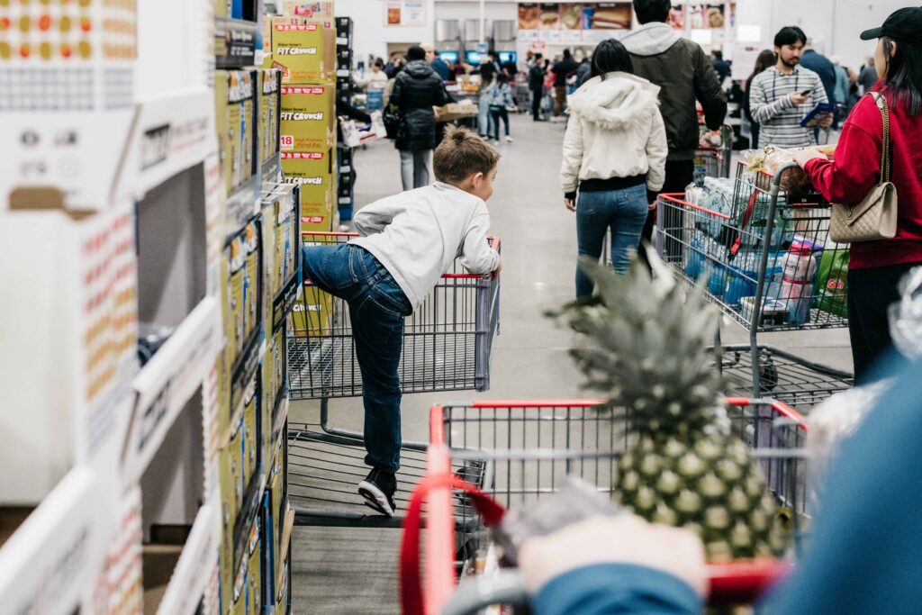 A boy sits in a shopping cart while his dad pushes it during a trip to COSTCO during a documentary family photography session by These Days Photography in Fairfax, VA