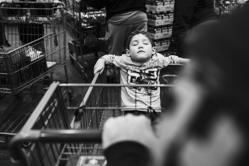 A boy sits in a shopping cart during a COSTCO trip during a documentary family photography session in Fairfax, VA