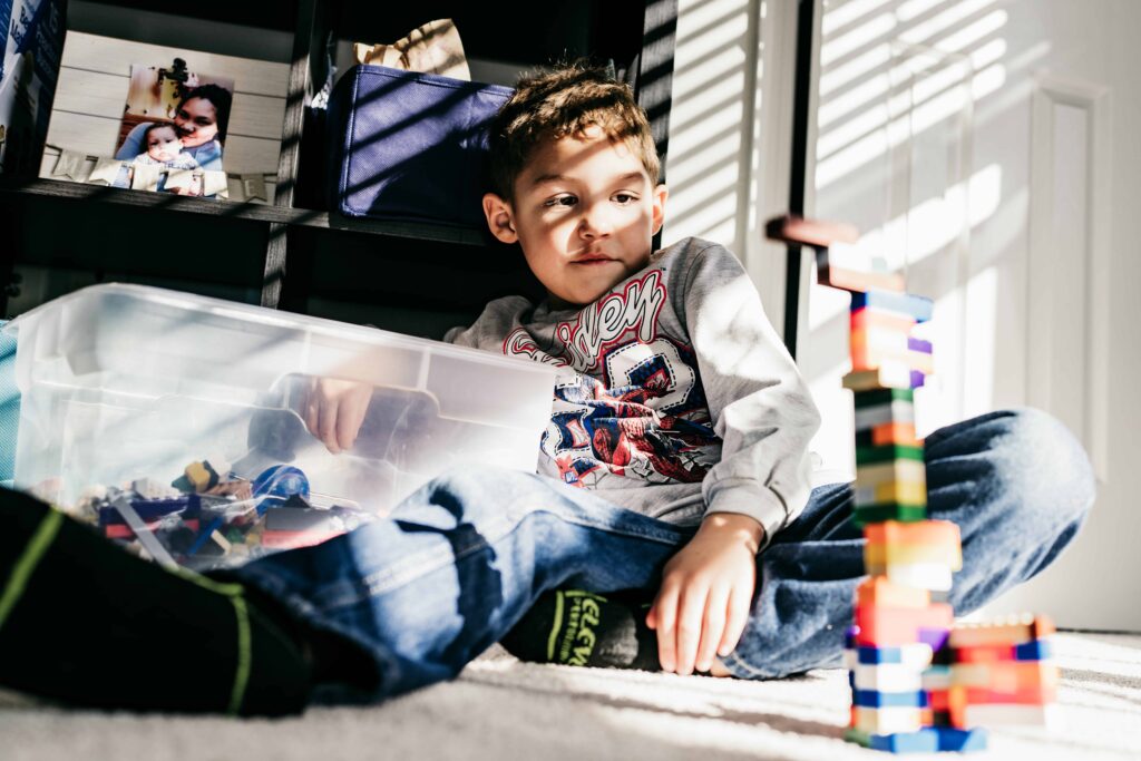 A boy builds a lego tower during a documentary family photography session by These Days Photography in Fairfax, VA