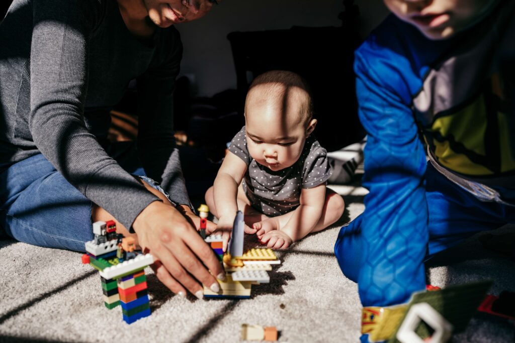 A mom plays with her baby and son building legos during a documentary family photography session by These Days Photography in Fairfax, VA